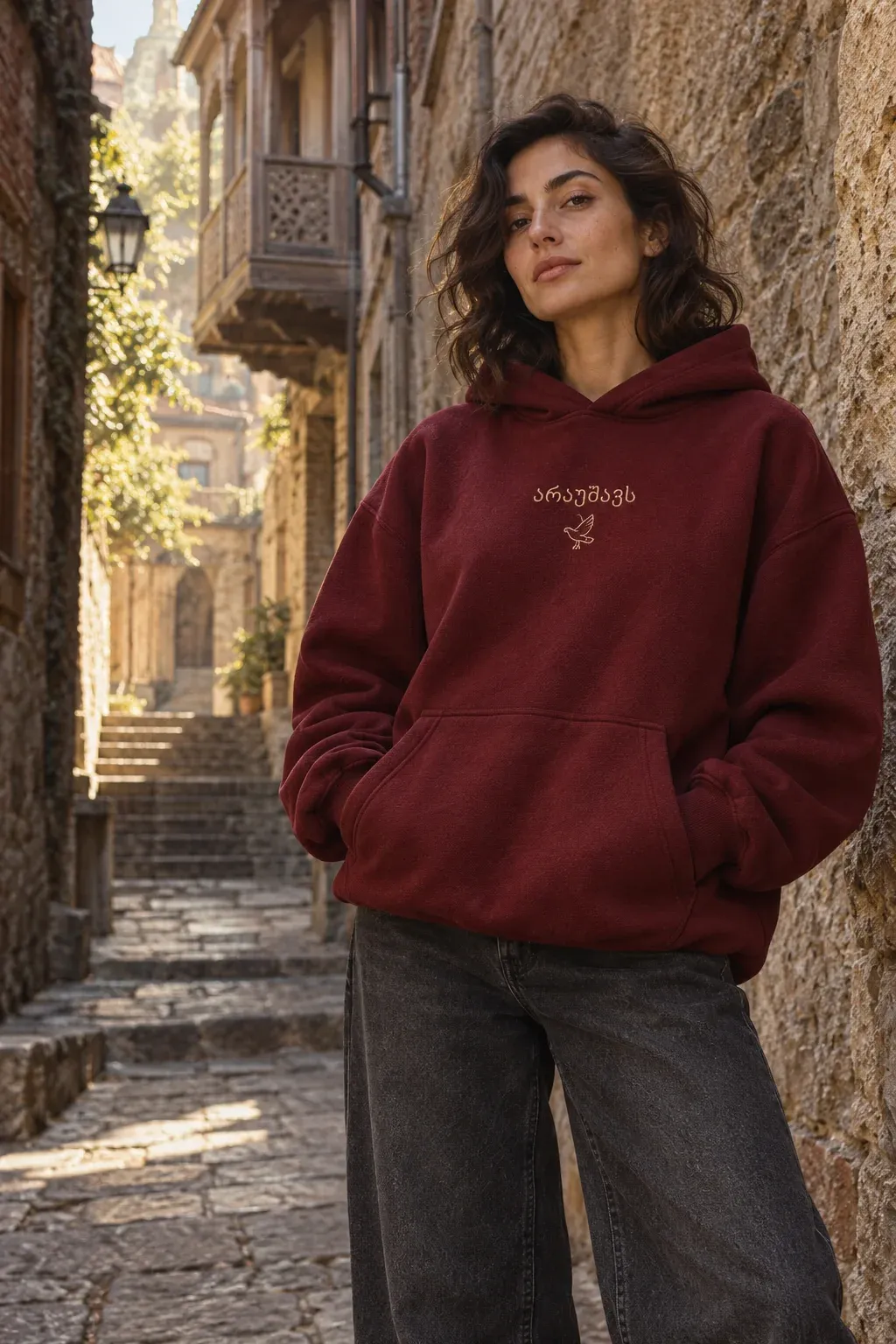 Woman in a wine-red Araushavs hoodie in a Tbilisi courtyard